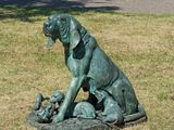 une statue représentant un chien avec une ribambelle de bébés dans l'herbe