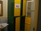 des casiers jaunes et verts dans une salle de bains équipée d'un lavabo et d'un miroir