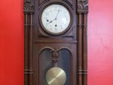 a clock that is sitting on the floor in front of a red wall