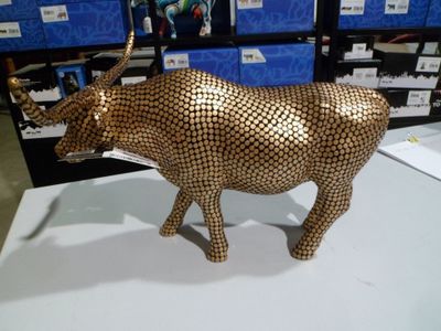 une statue de vache en or posée sur une table blanche dans un magasin