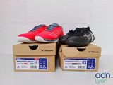 pair of red and black tennis shoes sitting on top of a cardboard box
