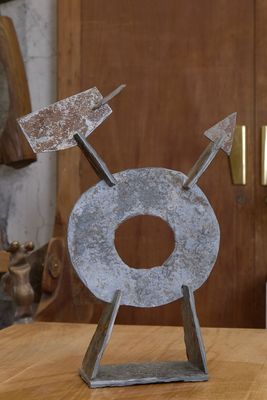 une sculpture en métal posée sur une table en bois dans une pièce