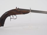 un vieux pistolet avec une poignée en bois sur une surface blanche