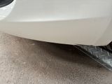 the front bumper of a white car with a flat tire
