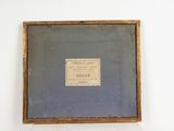 an old picture of a wooden frame with a plaque on it