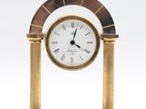 a gold clock on a marble table with a white background
