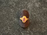 a close up of a ring with a red stone on a black surface