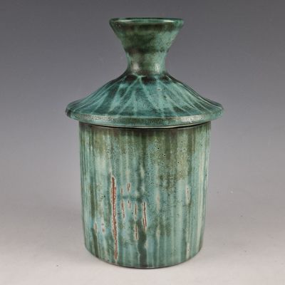 un vase vert muni d'un couvercle, posé sur une table