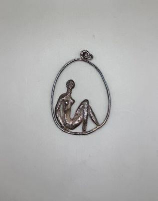 un pendentif en argent représentant une femme assise au sein d'un cercle