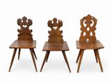 three wooden chairs with carved backrests sit side by side