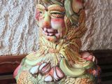 a ceramic figurine sitting on a wooden bench