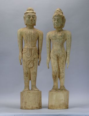 pair of carved wooden statues of a man and a woman standing next to each other