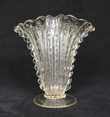 a glass vase on a stand on a black background