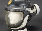 an old black and white helmet on a stand on a black background