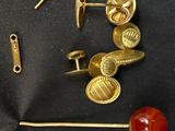 une paire de boutons de manchette en or et une boule rouge posée sur un tissu noir