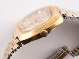 a gold watch that is sitting on a white surface