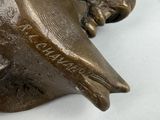a bronze statue of a bird on a white surface