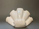 a white shell shaped bowl sitting on a gray surface