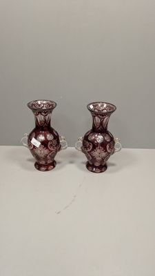 une paire de vases en verre violet posés sur une table blanche