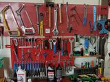 a red pegboard with lots of tools hanging on it