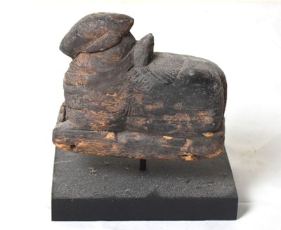 statue d'une vache coiffée d'un chapeau, assise sur un bloc de bois