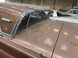 a brown car parked in a garage with other cars in the background