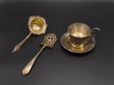deux cuillères en argent et une tasse posées sur un fond noir