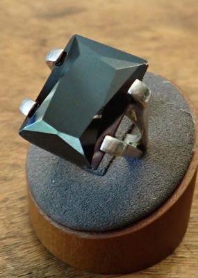 a ring with a black stone in it on a wooden stand