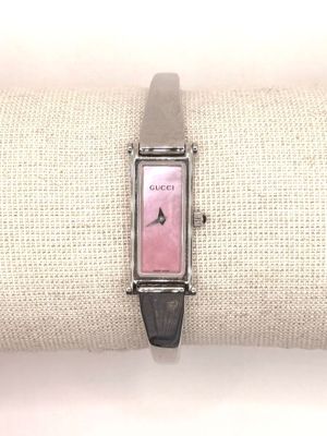 a pink watch on a black leather band on a white pillow