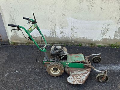 a small green lawn mower sitting on the pavement