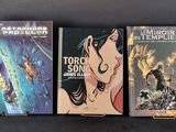 three books are lined up on a table with a black background