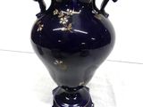 a blue vase with gold flowers on it on a white surface