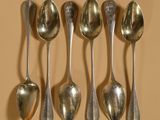six cuillères sont alignées sur une table