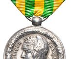 un gros plan d'une médaille sur fond blanc, ornée d'un ruban vert et jaune