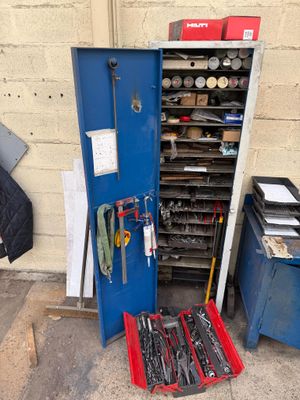 a blue cabinet with tools in it next to a blue trash can