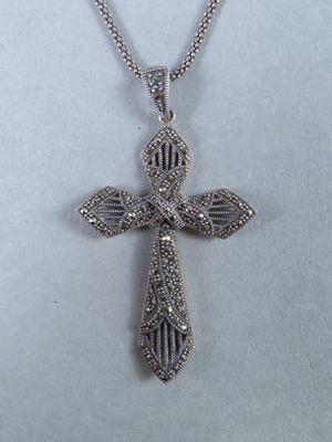 un pendentif en forme de croix en argent avec une chaîne, sur fond blanc