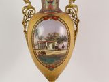 a gold vase with a picture on it on a stand