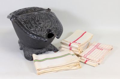 une petite théière noire, avec des serviettes et un torchon posés sur la table