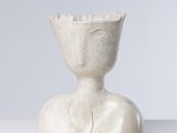 une sculpture blanche représentant une personne assise sur une table