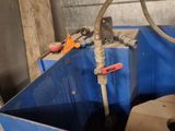 a blue container with a metal handle and a hose attached to it