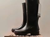 pair of black rain boots sitting on top of a cardboard box