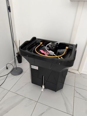 une poubelle noire posée par terre à côté d'un lampadaire