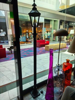 Des vases aux couleurs vives sont disposés devant une vitrine dans un centre commercial