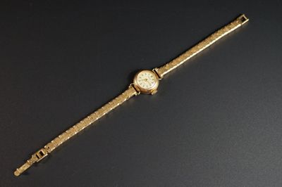 une image représentant une montre-bracelet en or posée sur une surface noire