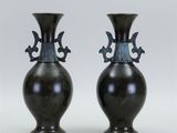 pair of black vases sitting on top of each other on a white surface