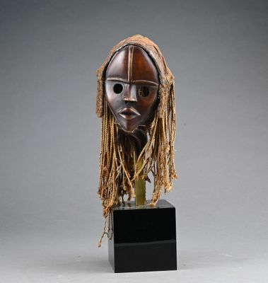an image of a wooden mask with dreadlocks on a stand