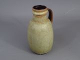 un vase marron muni d'une anse marron sur un fond gris