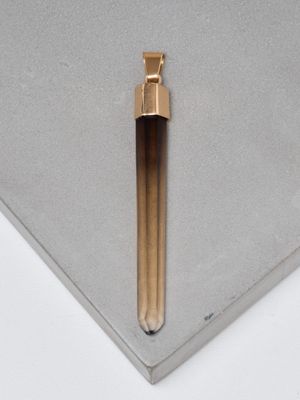un petit objet métallique posé sur une surface blanche, à côté d'un autre petit objet métallique