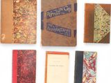 several old books are lined up on a white surface
