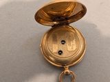 a gold pocket watch sitting on a white surface